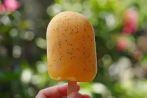 Close-up of a realistic mango-shaped ice cream popsicle held outdoors