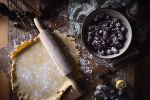 Preparing blackberry pie with frozen blackberries, crust and filling staged on a rustic table