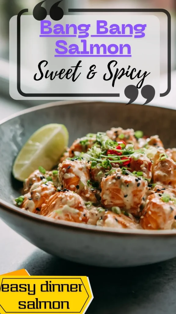 Side-view bowl of diced salmon bites glazed in creamy bang bang sauce, topped with sesame seeds and scallions, with a lime wedge on the side.