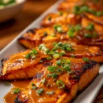 Plate of Bang Bang Salmon garnished with green onions and sesame seeds