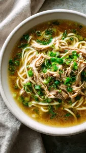 Aromatic Ginger Garlic Chicken Noodle Soup in a bowl with herbs and noodles