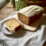 Sourdough carrot cake loaf topped with cream cheese frosting and walnuts.