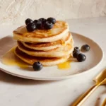 Fluffy sourdough lemon ricotta pancakes stacked on a plate with syrup