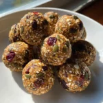 Pumpkin seed and cranberry energy balls stacked on a plate.