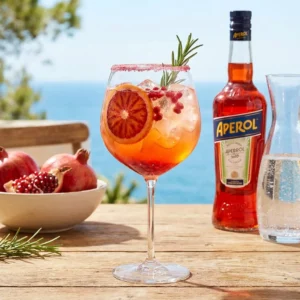 Aperol Spritz cocktail garnished with pomegranate seeds and orange slice.