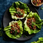 Asian chicken lettuce wraps garnished with vegetables and sauce
