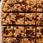 Baked oatmeal bars displayed on a rustic wooden table with fresh fruit.