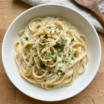 High Protein Alfredo Sauce in a bowl with pasta and fresh herbs
