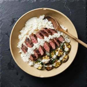 Grilled flank steak bowl with zucchini and creamy sauce served in a dish