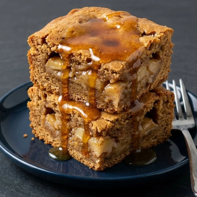 Maple glazed apple blondies served on a plate with a drizzle of maple syrup.