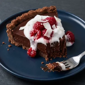 No-bake vegan chocolate tart topped with fresh berries and nuts
