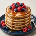 Fluffy sourdough pancakes topped with fresh blueberries on a plate.